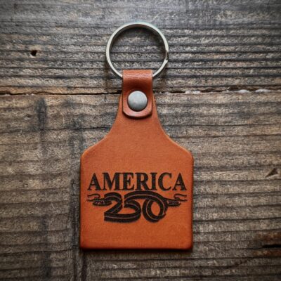 “Handcrafted America 250 Leather Keychain – Rustic cattle tag style key fob celebrating the USA 250th Anniversary (1776-2026). Premium full-grain leather, perfect patriotic gift for 4th of July, veterans & history lovers. Made in the USA.”